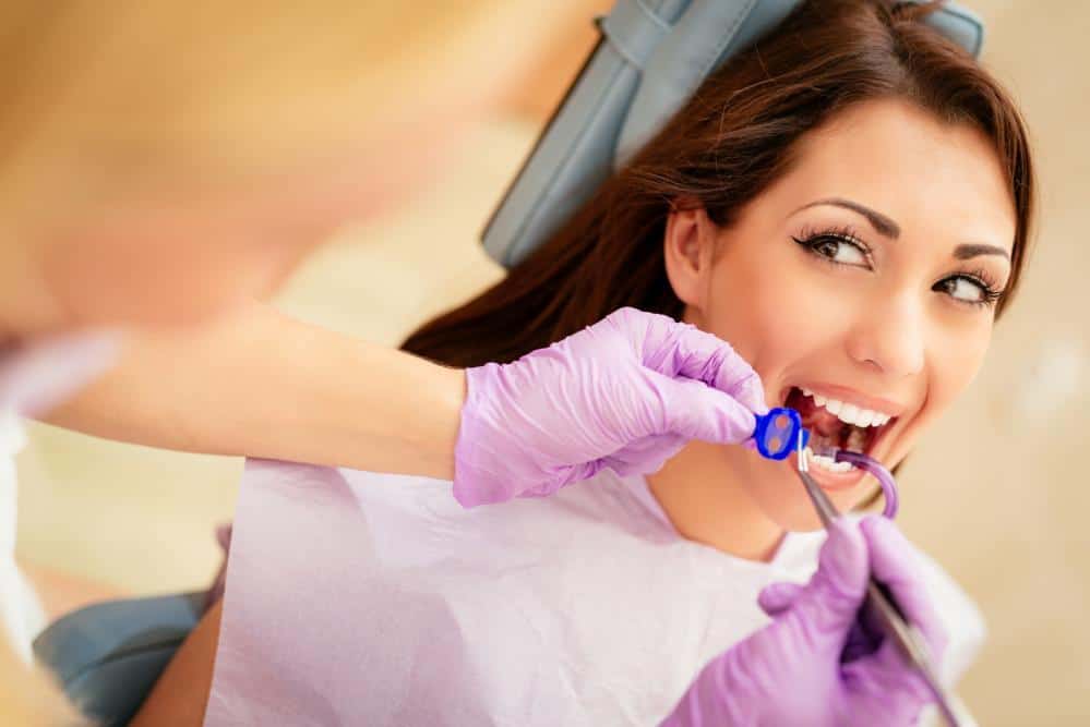 Woman sitting in a chair while dentist examines teeth